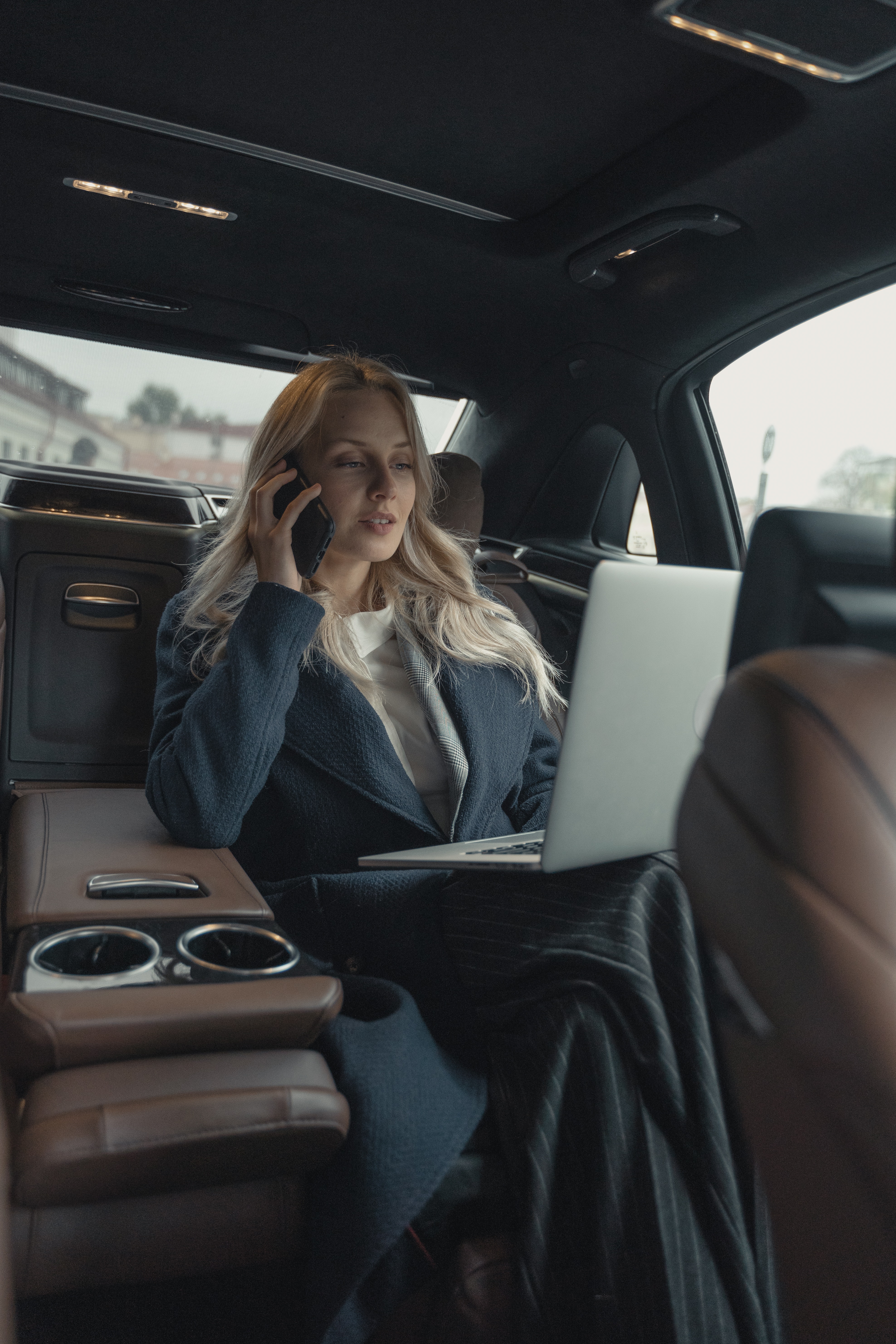Femme dans une voiture avec son ordinateur portable et son téléphone