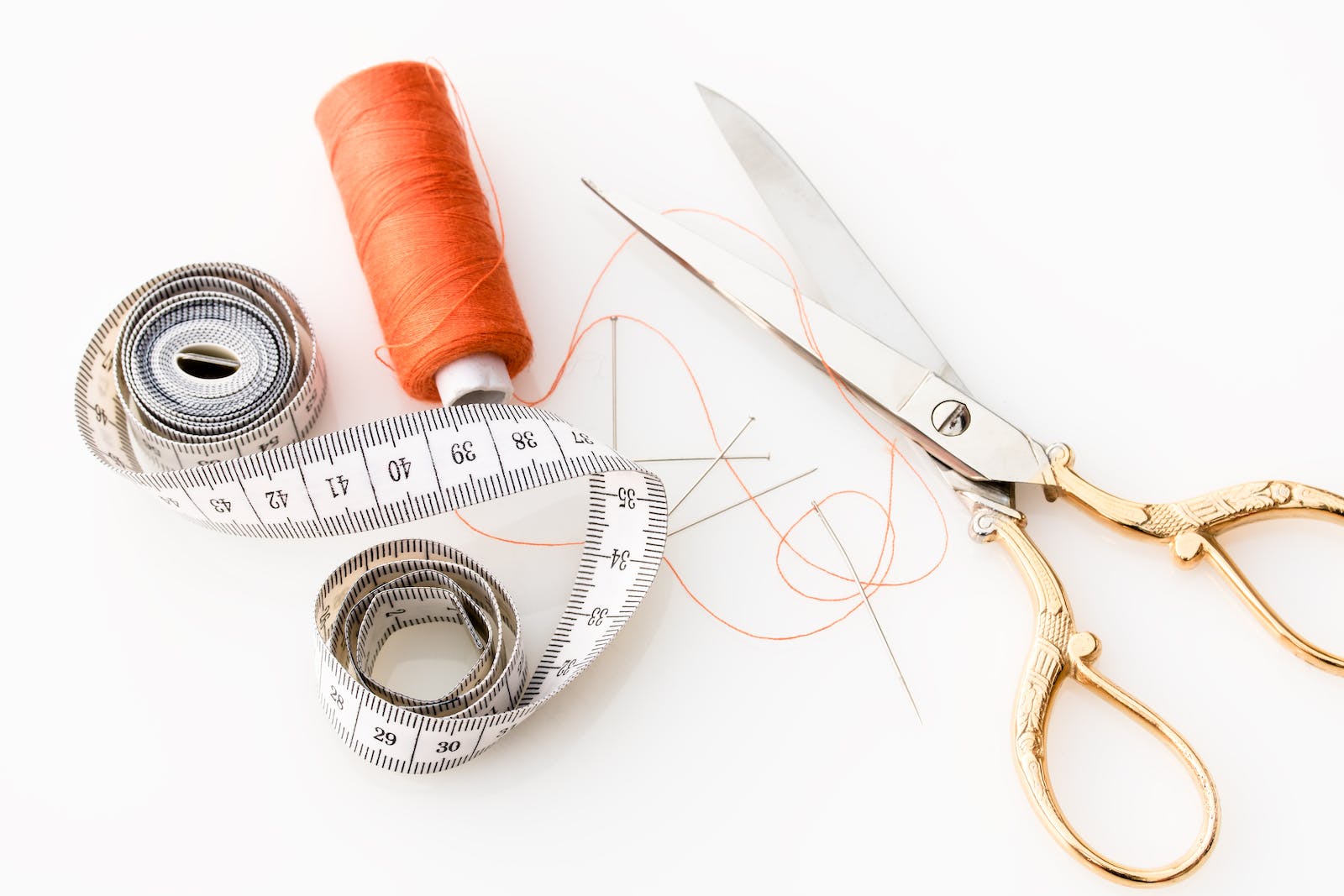 Des ciseaux, une bobines de fil et un mètre de couture